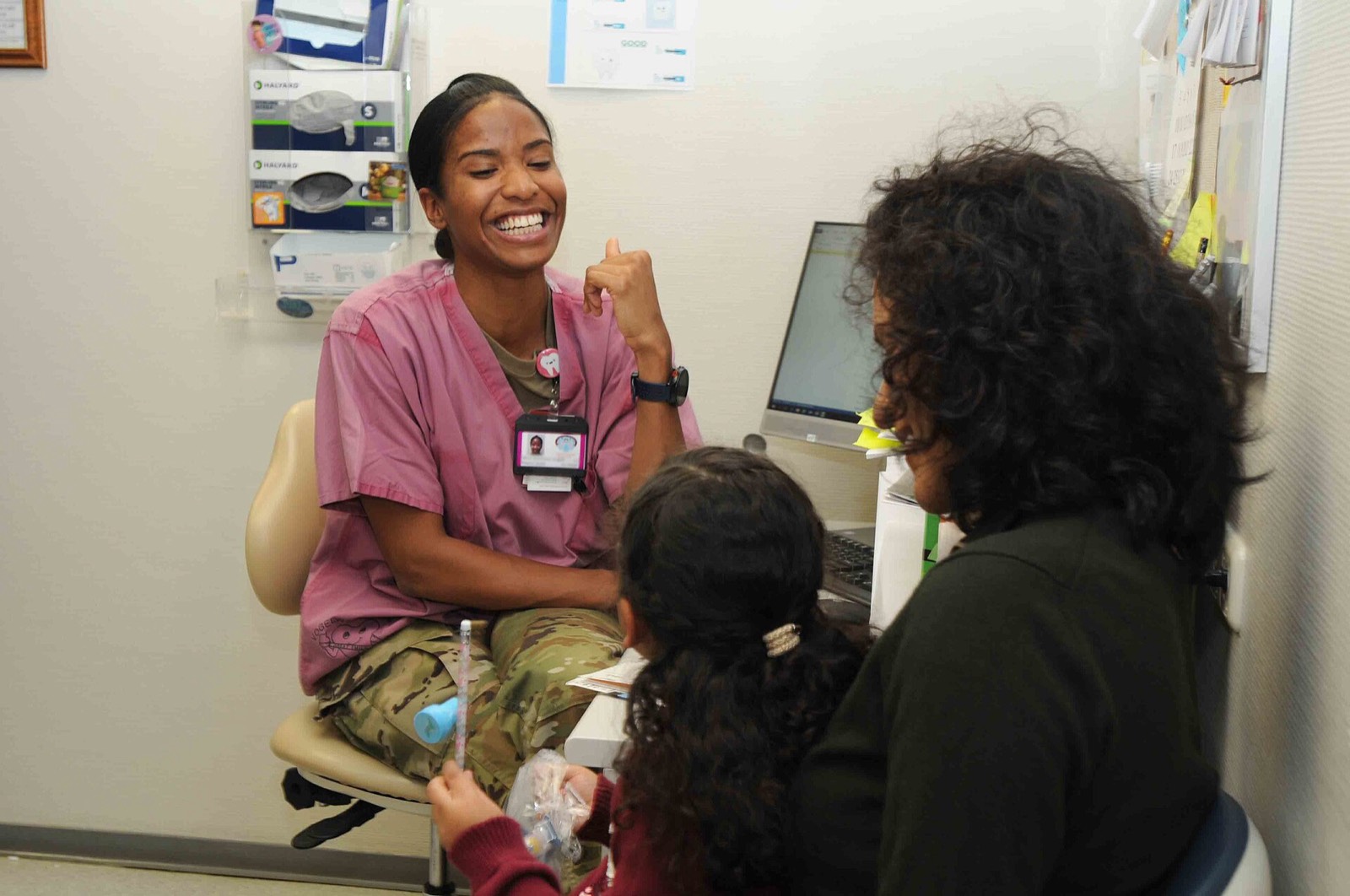 A smiling dentist with a mother and her young daughter