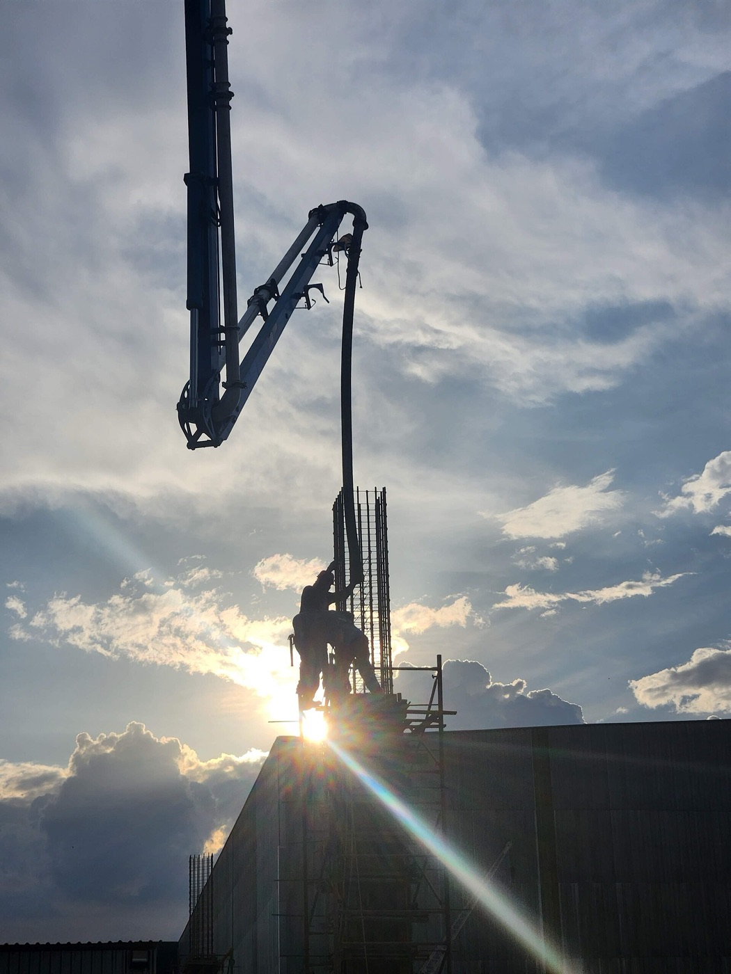 A concrete pump boom against a low sun