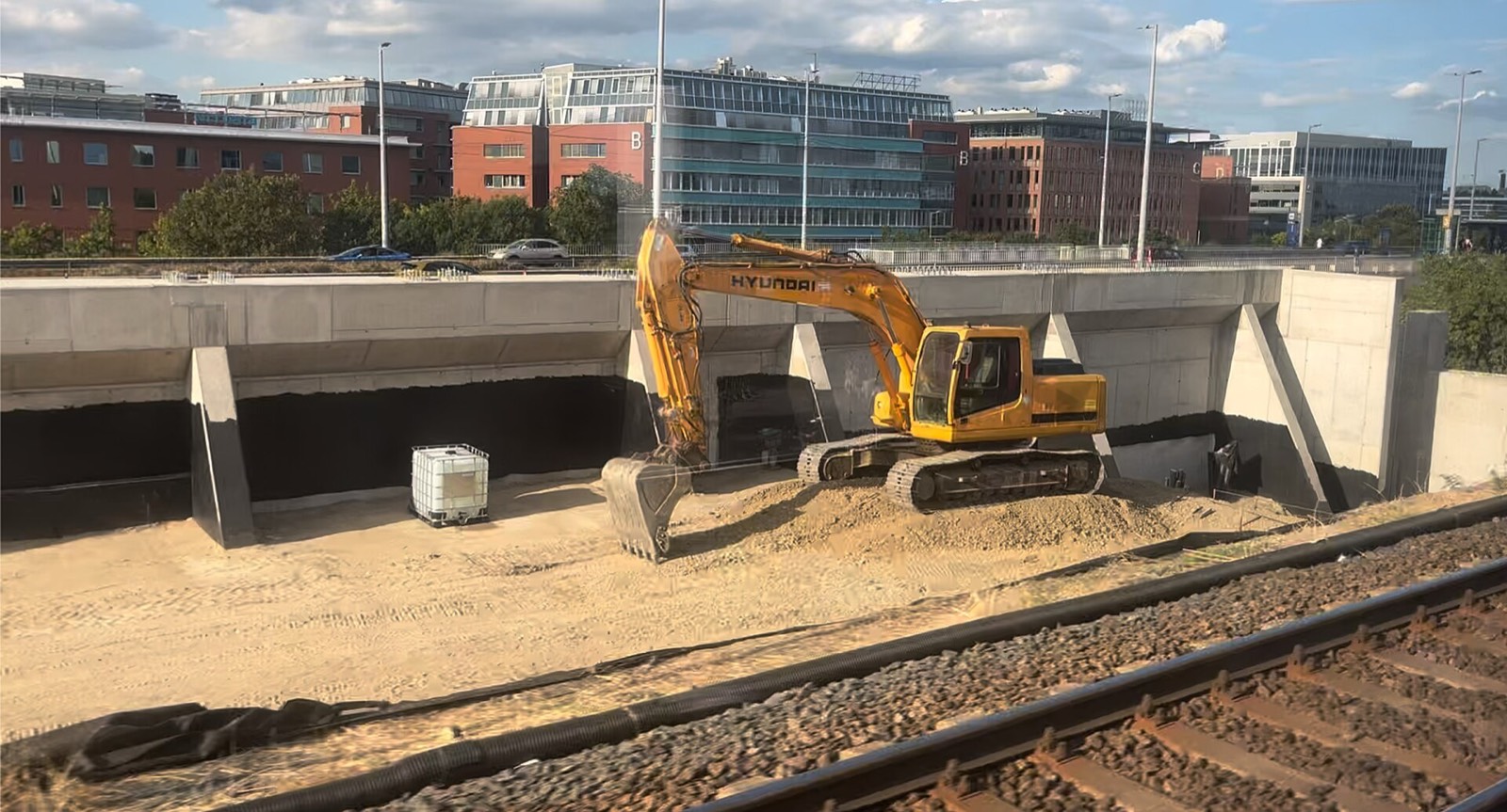 An excavator digging beside a concrete wall